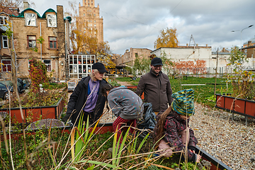 Image showing A modern family parents and children, is working together to beautify their front yard with flowers in preparation for the upcoming holiday season.