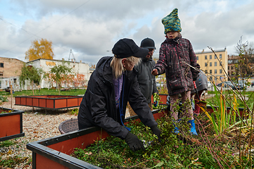 Image showing A modern family parents and children, is working together to beautify their front yard with flowers in preparation for the upcoming holiday season.