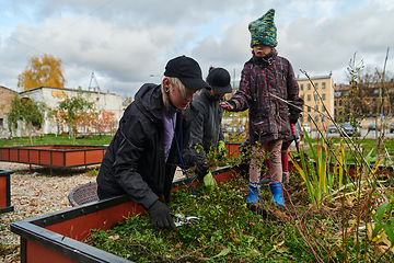 Image showing A modern family parents and children, is working together to beautify their front yard with flowers in preparation for the upcoming holiday season.