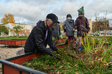 Image showing A modern family parents and children, is working together to beautify their front yard with flowers in preparation for the upcoming holiday season.