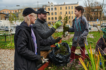 Image showing A modern family parents and children, is working together to beautify their front yard with flowers in preparation for the upcoming holiday season.