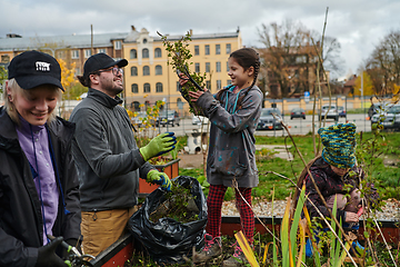 Image showing A modern family parents and children, is working together to beautify their front yard with flowers in preparation for the upcoming holiday season.