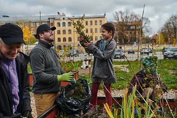 Image showing A modern family parents and children, is working together to beautify their front yard with flowers in preparation for the upcoming holiday season.