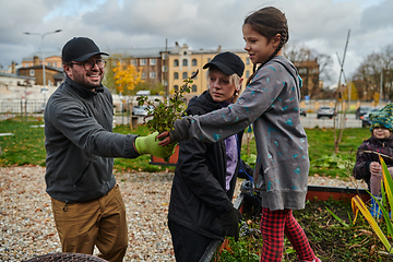 Image showing A modern family parents and children, is working together to beautify their front yard with flowers in preparation for the upcoming holiday season.