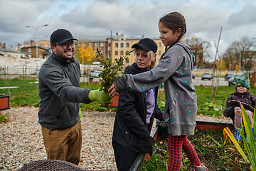 Image showing A modern family parents and children, is working together to beautify their front yard with flowers in preparation for the upcoming holiday season.