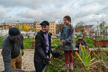 Image showing A modern family parents and children, is working together to beautify their front yard with flowers in preparation for the upcoming holiday season.