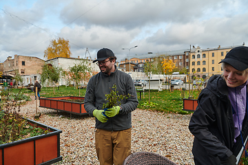 Image showing A modern family parents and children, is working together to beautify their front yard with flowers in preparation for the upcoming holiday season.