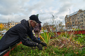 Image showing A modern family parents and children, is working together to beautify their front yard with flowers in preparation for the upcoming holiday season.