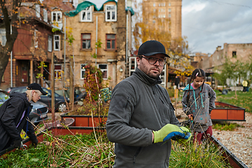 Image showing A modern family parents and children, is working together to beautify their front yard with flowers in preparation for the upcoming holiday season.