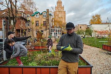 Image showing A modern family parents and children, is working together to beautify their front yard with flowers in preparation for the upcoming holiday season.