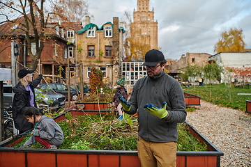 Image showing A modern family parents and children, is working together to beautify their front yard with flowers in preparation for the upcoming holiday season.