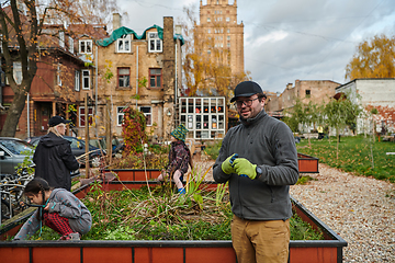 Image showing A modern family parents and children, is working together to beautify their front yard with flowers in preparation for the upcoming holiday season.