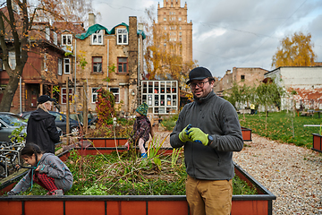 Image showing A modern family parents and children, is working together to beautify their front yard with flowers in preparation for the upcoming holiday season.