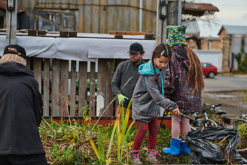 Image showing A modern family parents and children, is working together to beautify their front yard with flowers in preparation for the upcoming holiday season.