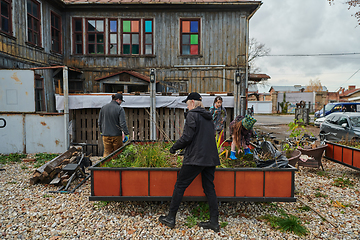 Image showing A modern family parents and children, is working together to beautify their front yard with flowers in preparation for the upcoming holiday season.