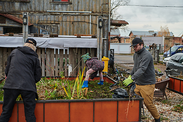 Image showing A modern family parents and children, is working together to beautify their front yard with flowers in preparation for the upcoming holiday season.