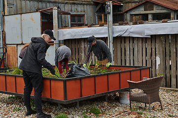 Image showing A modern family parents and children, is working together to beautify their front yard with flowers in preparation for the upcoming holiday season.