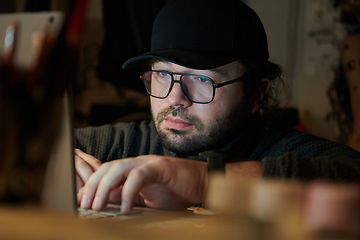 Image showing A close-up shot of a man using a laptop in a dimly lit room, engrossed in his digital work during the late hours of the night