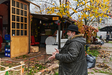 Image showing In the historic city of Riga, a bearded elderly man passionately explains the traditional symbolism of Halloween, connecting generations through cultural heritage and folklore.