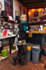 Image showing A modern and intriguing girl with striking blue hair enjoys a night out in a cafe transformed into a passionate Halloween-style setting, exuding a captivating and witchy ambiance