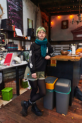 Image showing A modern and intriguing girl with striking blue hair enjoys a night out in a cafe transformed into a passionate Halloween-style setting, exuding a captivating and witchy ambiance