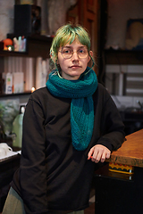 Image showing A modern and intriguing girl with striking blue hair enjoys a night out in a cafe transformed into a passionate Halloween-style setting, exuding a captivating and witchy ambiance