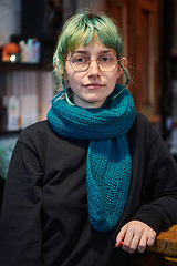 Image showing A modern and intriguing girl with striking blue hair enjoys a night out in a cafe transformed into a passionate Halloween-style setting, exuding a captivating and witchy ambiance