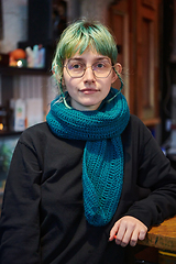 Image showing A modern and intriguing girl with striking blue hair enjoys a night out in a cafe transformed into a passionate Halloween-style setting, exuding a captivating and witchy ambiance