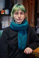 Image showing A modern and intriguing girl with striking blue hair enjoys a night out in a cafe transformed into a passionate Halloween-style setting, exuding a captivating and witchy ambiance