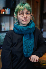 Image showing A modern and intriguing girl with striking blue hair enjoys a night out in a cafe transformed into a passionate Halloween-style setting, exuding a captivating and witchy ambiance