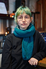 Image showing A modern and intriguing girl with striking blue hair enjoys a night out in a cafe transformed into a passionate Halloween-style setting, exuding a captivating and witchy ambiance