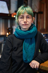 Image showing A modern and intriguing girl with striking blue hair enjoys a night out in a cafe transformed into a passionate Halloween-style setting, exuding a captivating and witchy ambiance