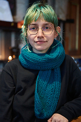 Image showing A modern and intriguing girl with striking blue hair enjoys a night out in a cafe transformed into a passionate Halloween-style setting, exuding a captivating and witchy ambiance