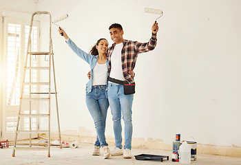 Image showing Portrait of happy couple painting the new living room in a home or apartment. Man and woman with paintbrush to decorate a wall color and renovation the house interior with smile or happiness together