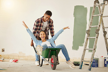 Image showing DIY, painting and happy couple smile while moving into new home, real estate property house or building. Love, creative man and woman on wheelbarrow interior design and renovation work on room wall