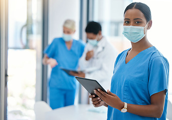 Image showing Healthcare, doctor or a nurse on a tablet, consulting in a hospital boardroom. Medical workers meeting to consult, communication online. Covid management and teamwork, doctors wearing surgical masks