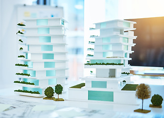 Image showing Building real estate model on a table in an architecture or construction business office. Creative 3d apartment or hotel design on a planning desk with blueprint paper in realtor company desk