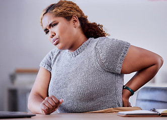 Image showing Corporate employee suffering from back pain while working at a desk in an office, uncomfortable and concerned. Young professional experience discomfort from an injury, bad posture or hurt muscle