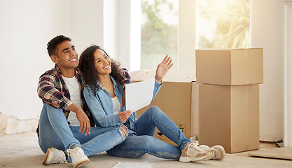 Image showing Couple happy on the floor of their new property or house in the living room with box in the background. Real estate owner smile inside the lounge interior thinking of idea for renovation at home