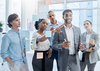 Image showing Teamwork, collaboration and planning with a team and their manager working on the vision, mission and strategy for their business. Writing on a glass wall with sticky notes for growth and development