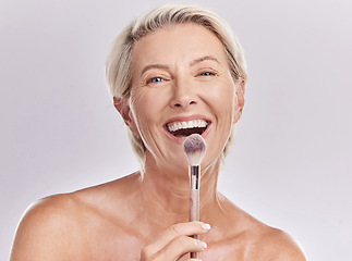 Image showing Beauty, makeup skincare with a senior model holding a blusher brush in studio against a gray background. Portrait of an elderly woman with a smile posing for wellness, healthcare and cosmetics