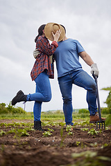 Image showing Farmer, love and couple kiss hiding with a hat on agriculture, sustainability and green farm showing new growth on soil. Environment, farm or countryside garden man and woman working on healthy earth