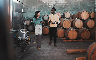 Image showing Wine cellar, warehouse and winery worker teaching a man about wine while he is writing notes. Winemaker walking in a distillery with wooden barrels and agriculture machines while consulting a partner