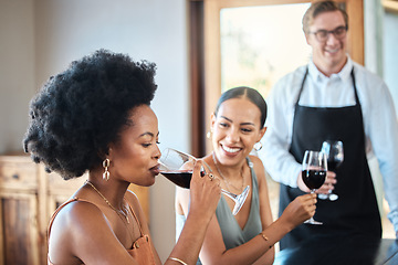 Image showing Beautiful women friends taste a red wine glass together for brunch party in a luxury restaurant. Happy woman with an afro drinking with her friend at a distillery restaurant for alcohol with a smile