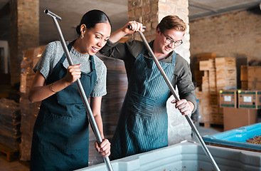 Image showing Cellar workers, making wine and mixing open tank with stirring, pressing and crushing tool for alcohol production. Happy staff and merchants in factory distillery, winery and manufacturing warehouse