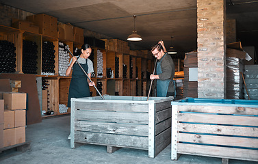 Image showing Vintners, wine merchants and cellar workers in production cellar, winery and factory distillery for manufacturing. Industry staff working together to stir, mix and crush an open tank and big crate