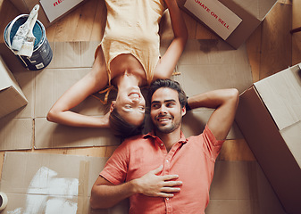 Image showing Home improvement, renovation and remodeling with a young couple lying on the floor together at home from above. Man and woman homeowners moving house, painting and unpacking boxes or packages