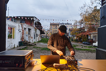 Image showing A young man is entertaining a group of friends in the backyard of his house, becoming their DJ and playing music in a casual outdoor gathering