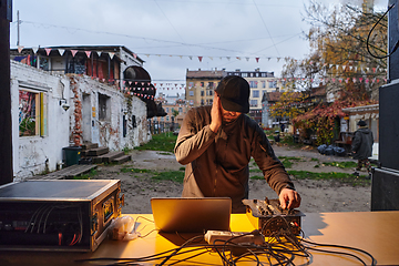 Image showing A young man is entertaining a group of friends in the backyard of his house, becoming their DJ and playing music in a casual outdoor gathering