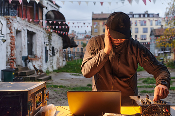 Image showing A young man is entertaining a group of friends in the backyard of his house, becoming their DJ and playing music in a casual outdoor gathering